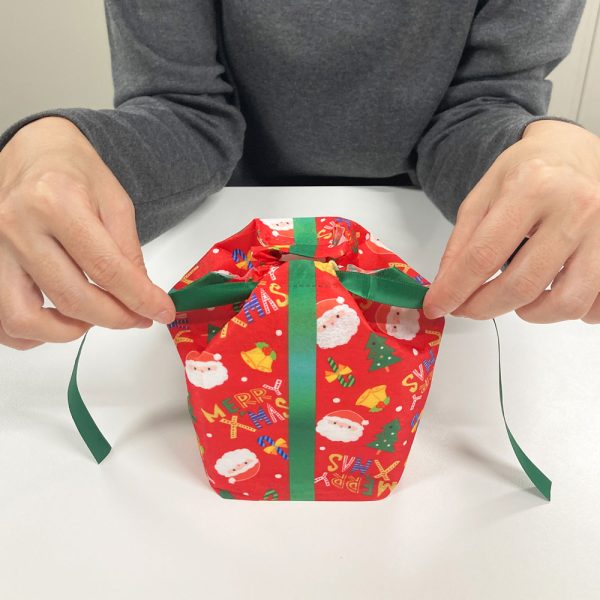 ハコ巾着クリスマス柄を結んでいるところ|クリスマス・正月・節分イベントにおすすめ